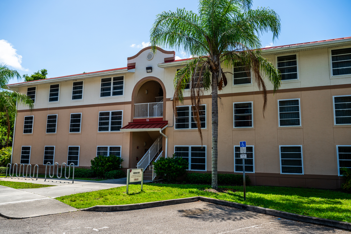 Anderson Hall surrounded by green grass, palm trees and blue sky